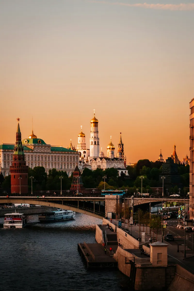 Московский Кремль с Большим Кремлёвским дворцом и колокольней Ивана Великого на закате, впереди Москва-река с мостом и теплоходами